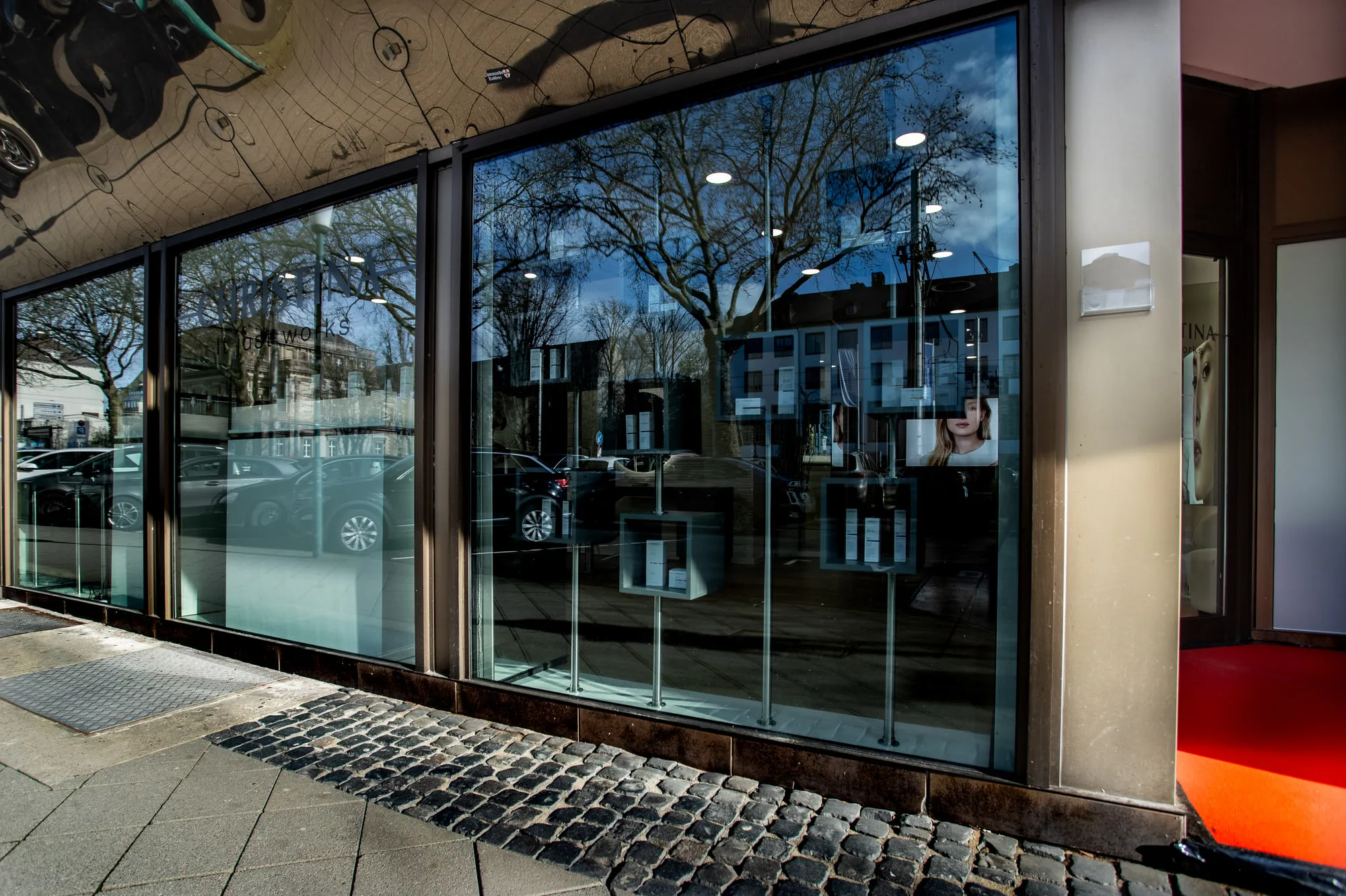Christina Kassel — the finished salon: oak floor, product wall and backlit round mirrors