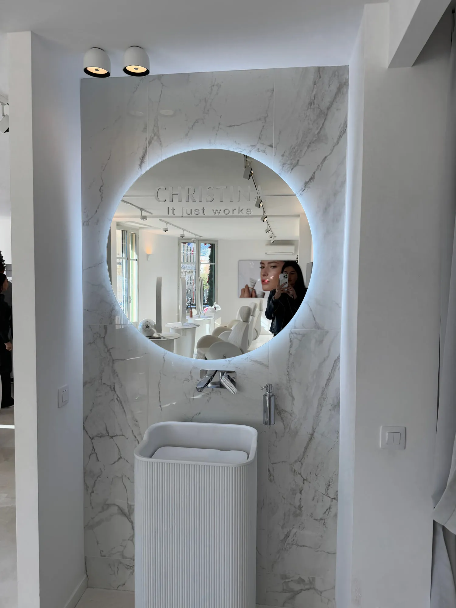 Christina Cannes — arched niches and lit oval mirrors along the salon