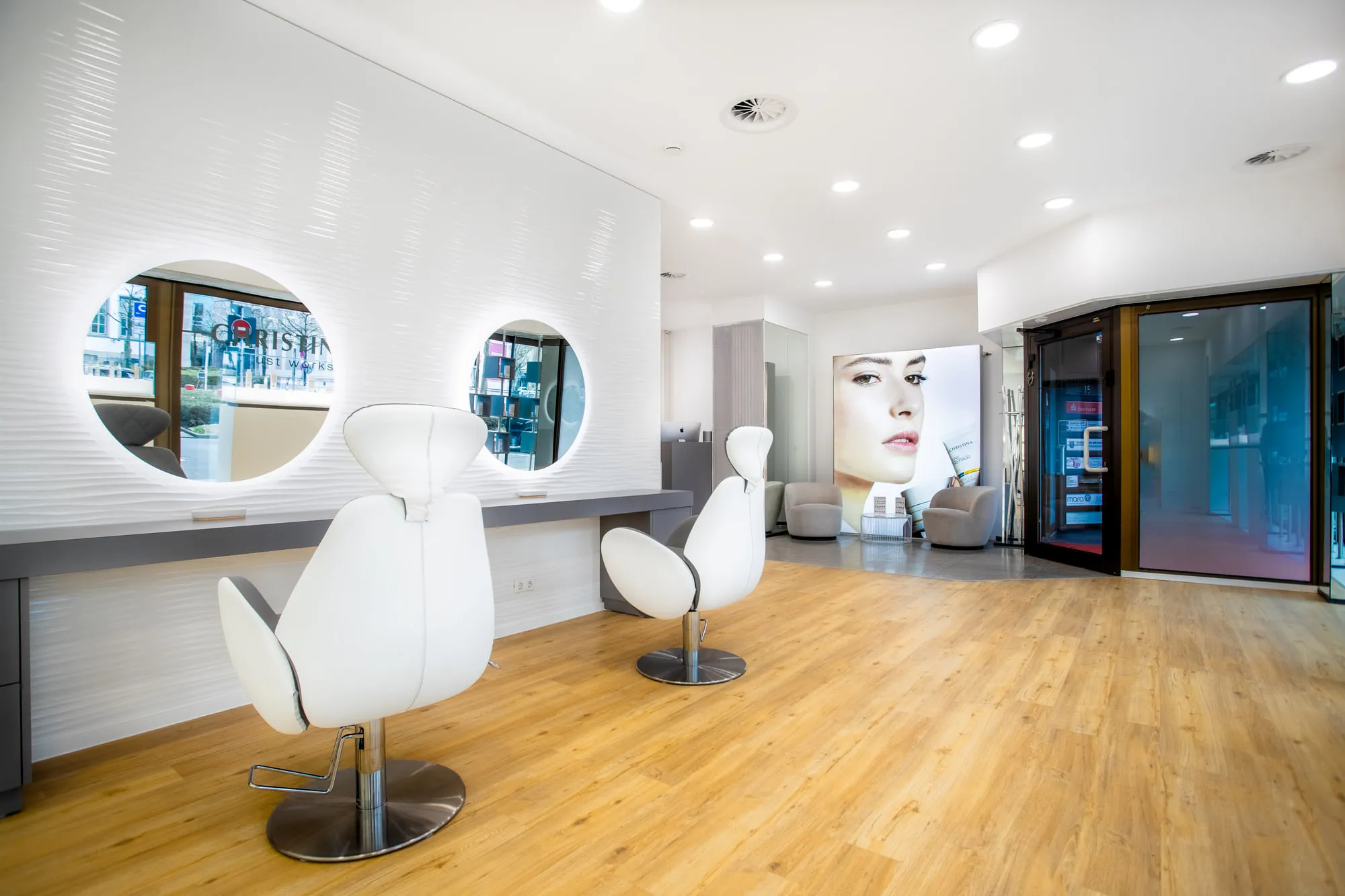 Christina Kassel — the finished salon: oak floor, product wall and backlit round mirrors