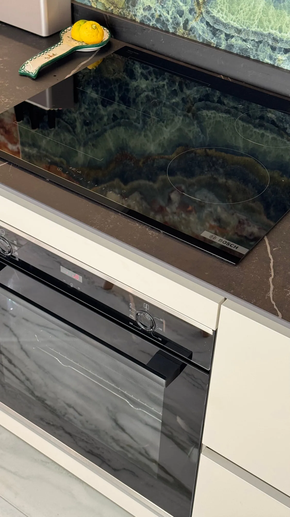 Appartamento Monza — green quartzite against matte lacquer and a black worktop