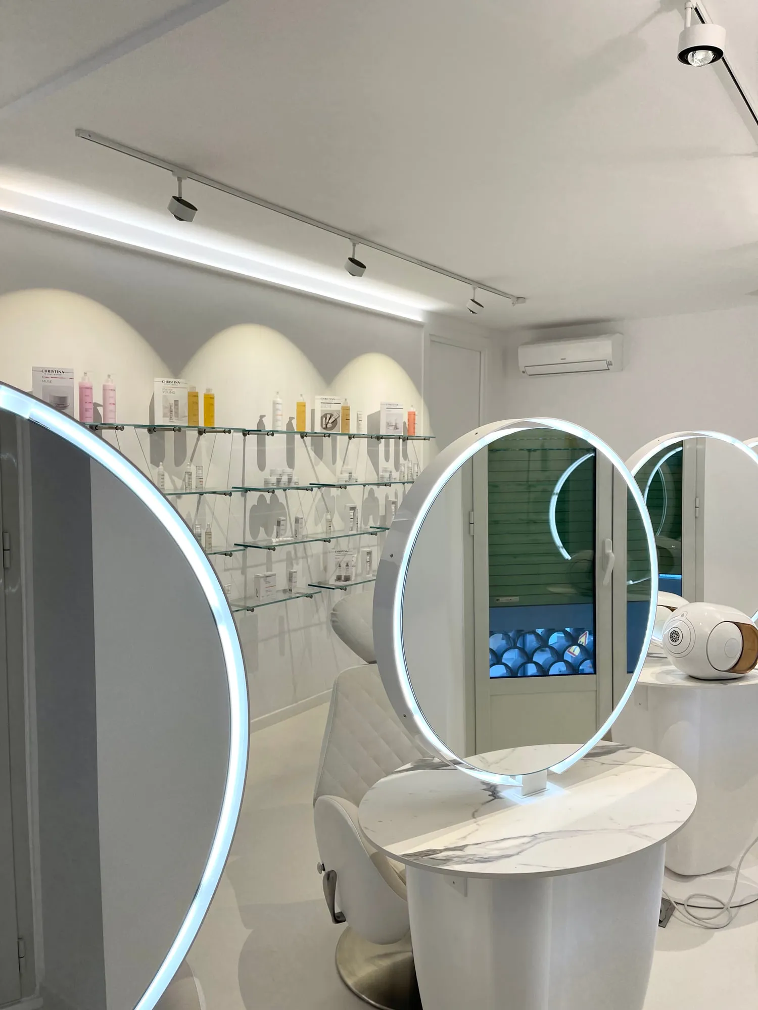 Christina Cannes — arched niches and lit oval mirrors along the salon