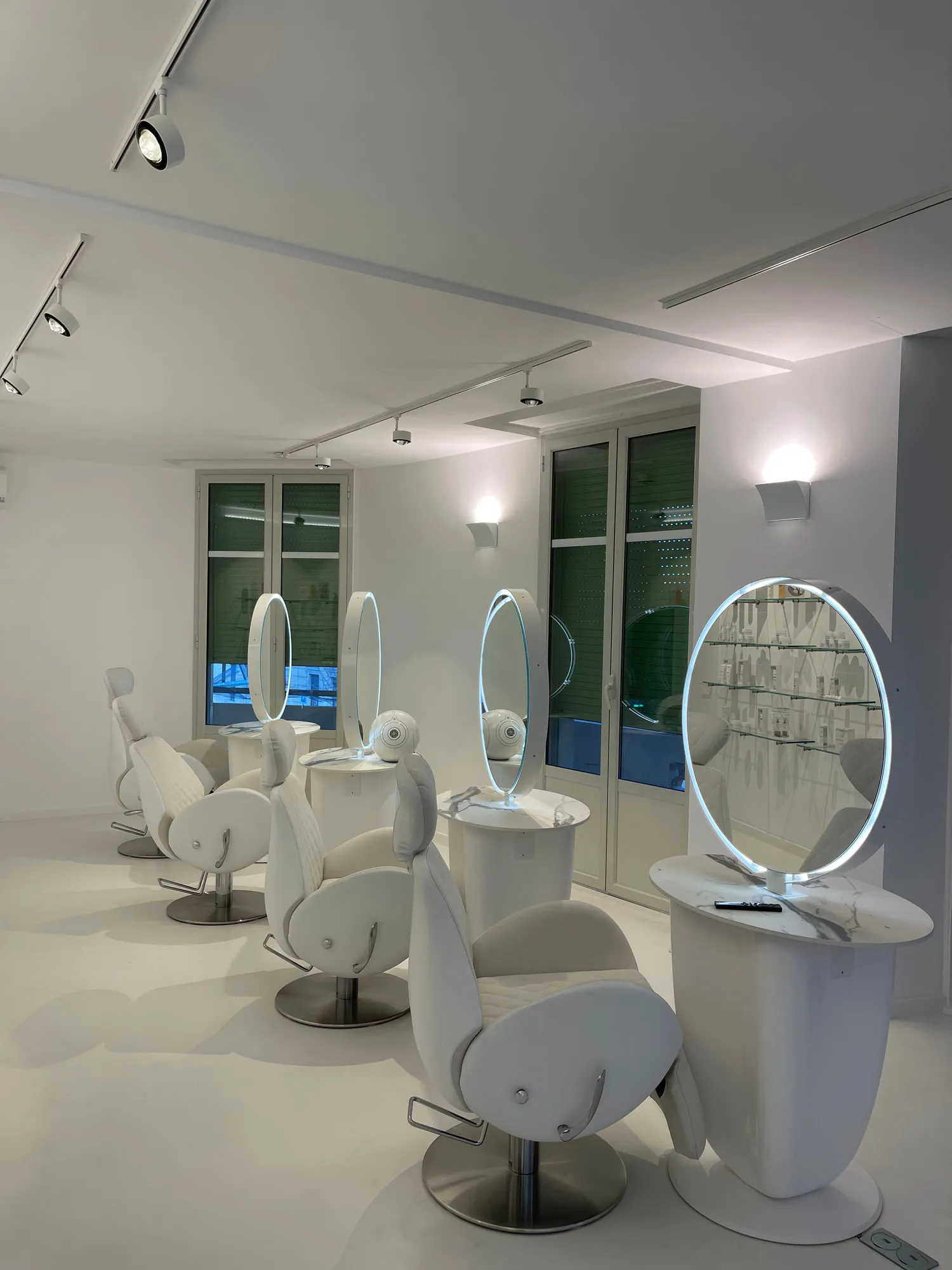 Christina Cannes — arched niches and lit oval mirrors along the salon