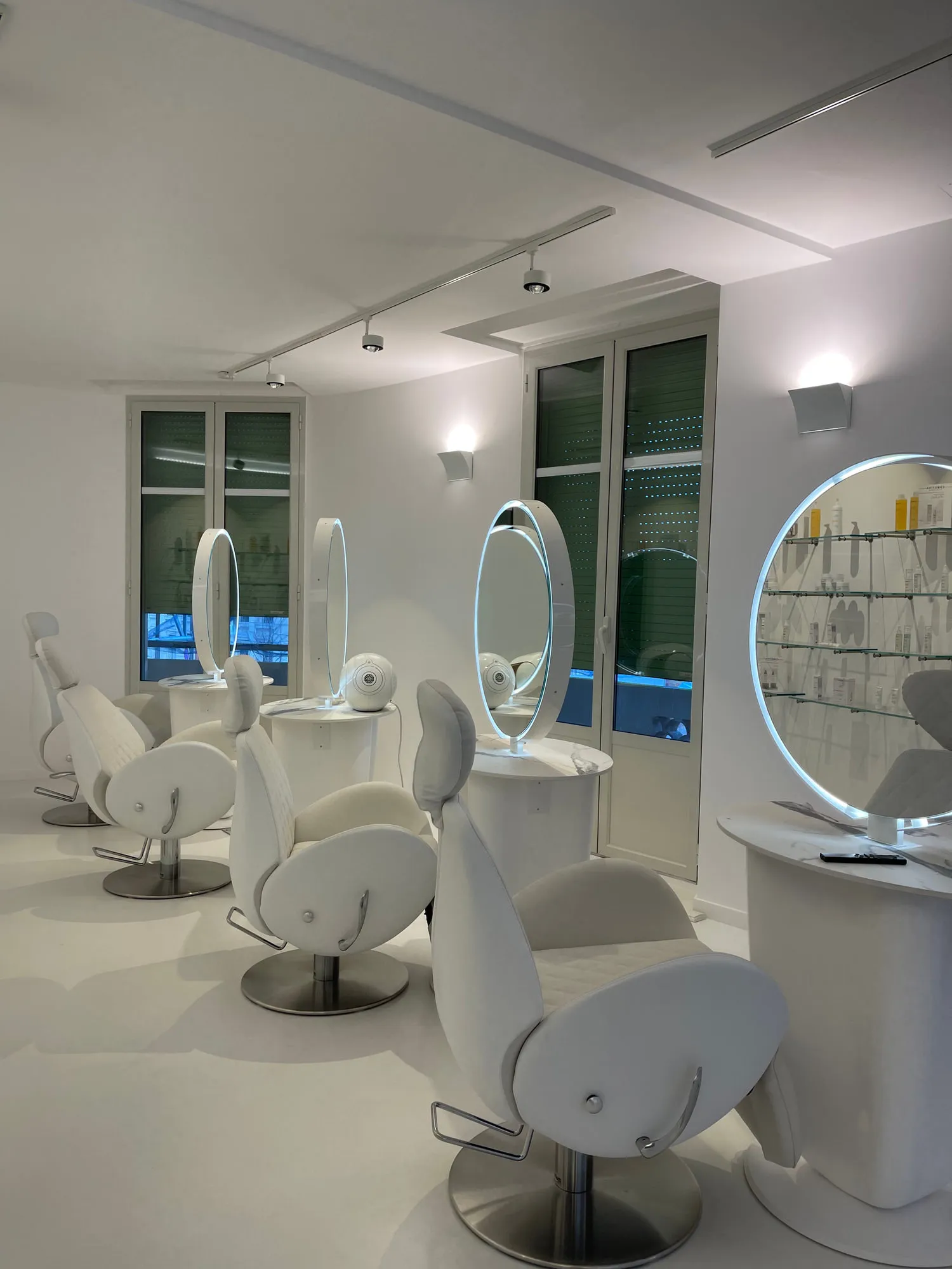 Christina Cannes — arched niches and lit oval mirrors along the salon