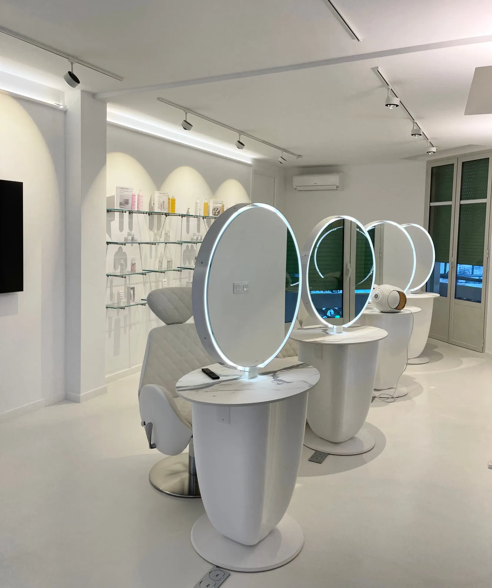 Christina Cannes — arched niches and lit oval mirrors along the salon