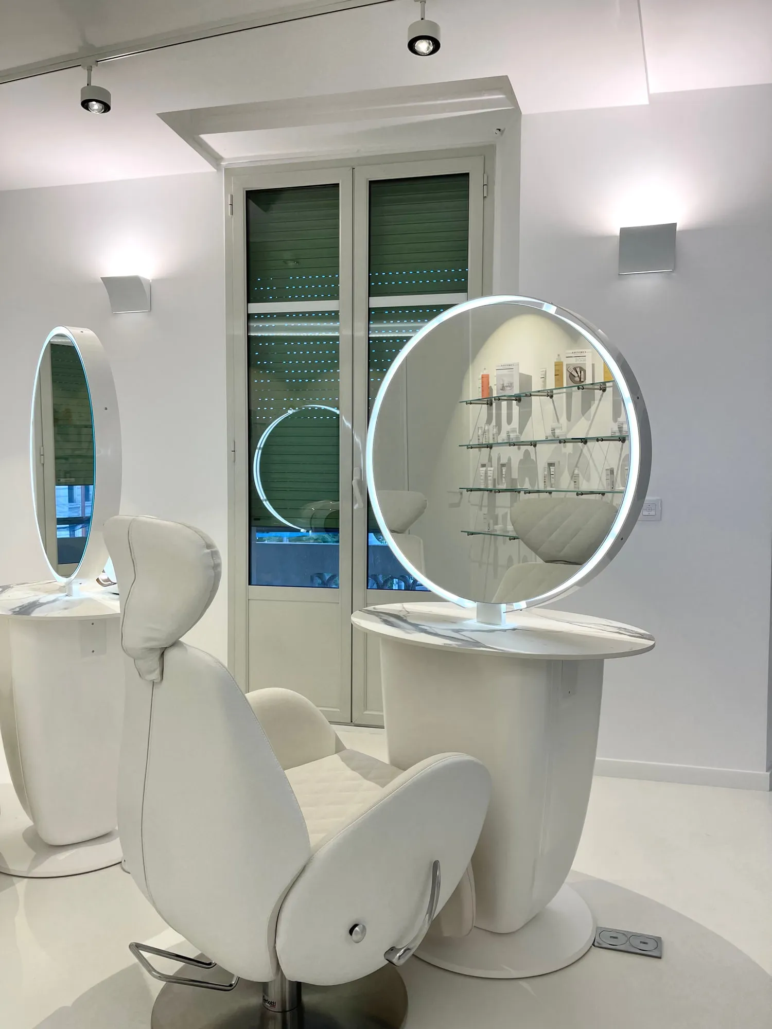 Christina Cannes — arched niches and lit oval mirrors along the salon