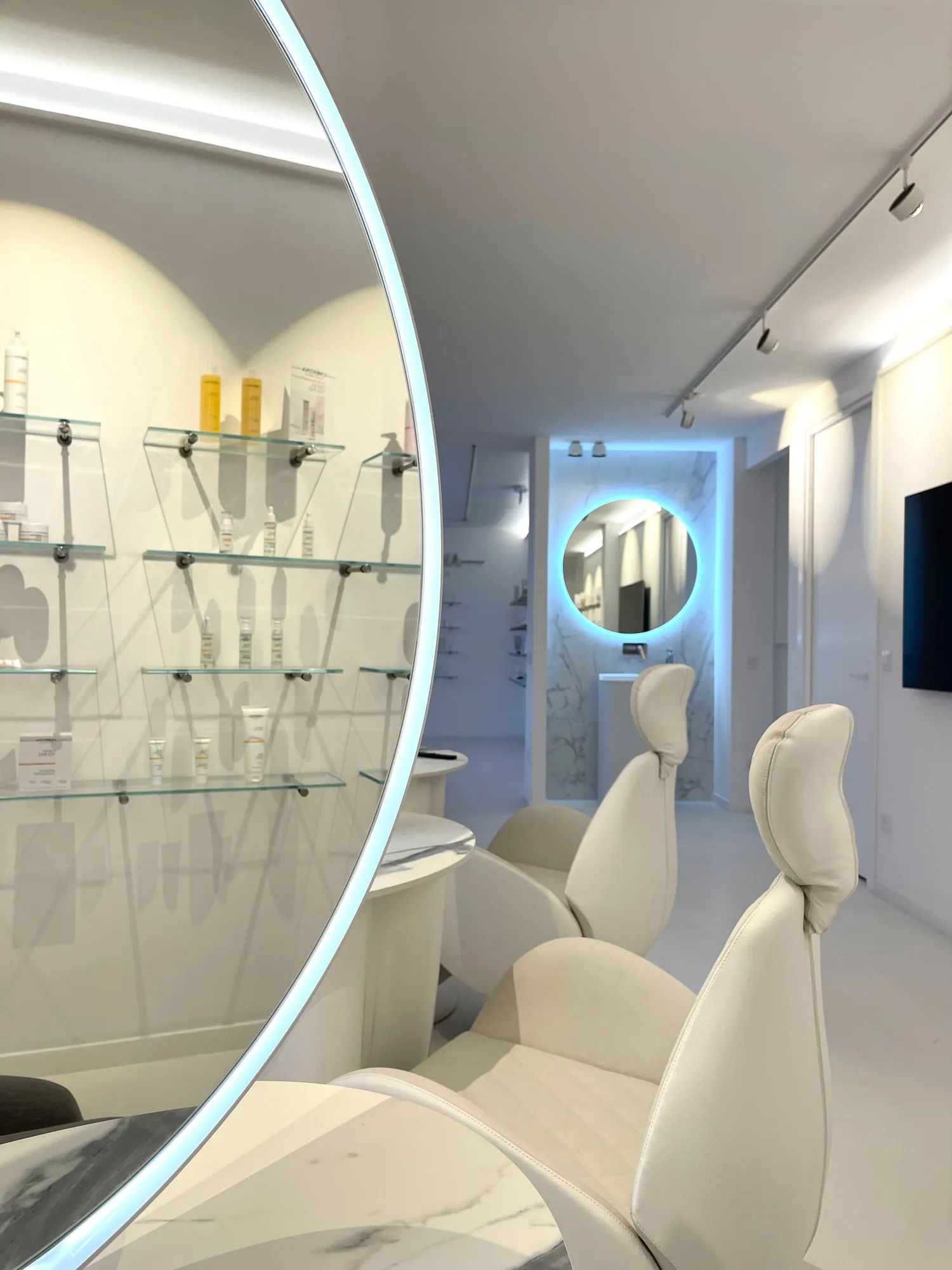 Christina Cannes — arched niches and lit oval mirrors along the salon