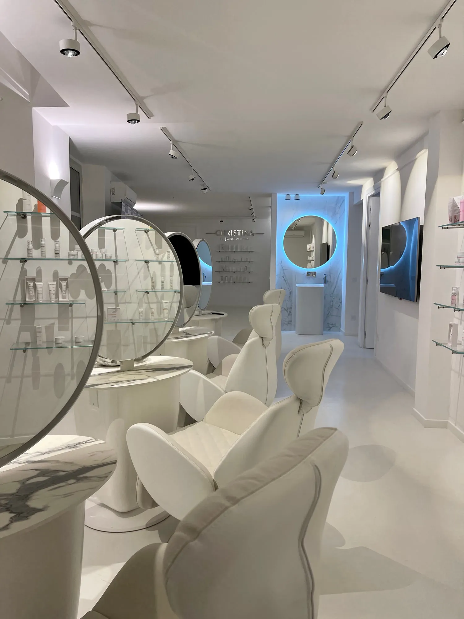 Christina Cannes — arched niches and lit oval mirrors along the salon