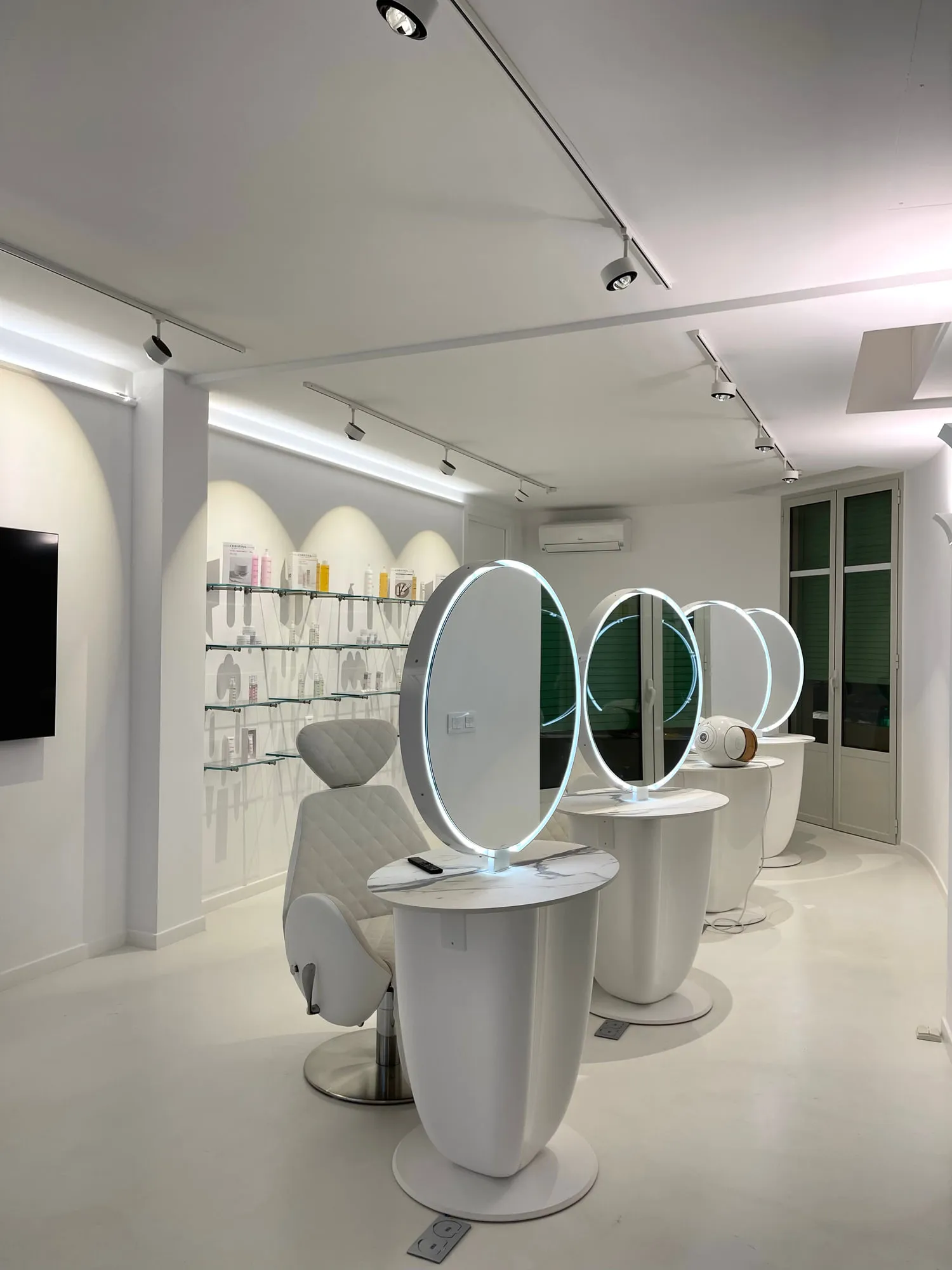 Christina Cannes — arched niches and lit oval mirrors along the salon