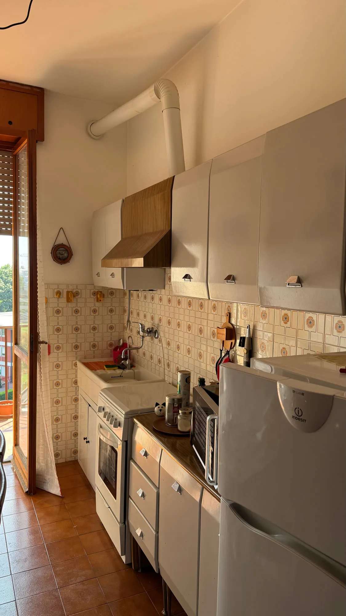 Before — The galley kitchen, from patterned tile to a single run of quartzite